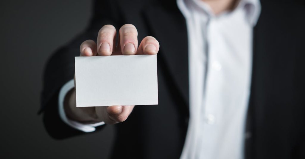 A man in a suit presenting a blank business card for corporate usage.